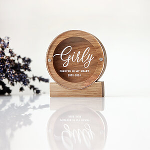 Round oak dog hair keepsake box standing upright on a wooden base with custom UV-printed name Girly on the clear acrylic lid.