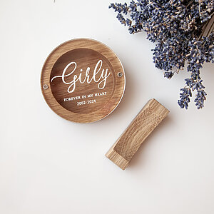 Top view of a round oak dog hair keepsake box with the name Girly UV-printed on the clear acrylic lid.