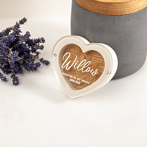 Personalized white heart dog hair keepsake box with Willow UV-printing next to a grey concrete urn.