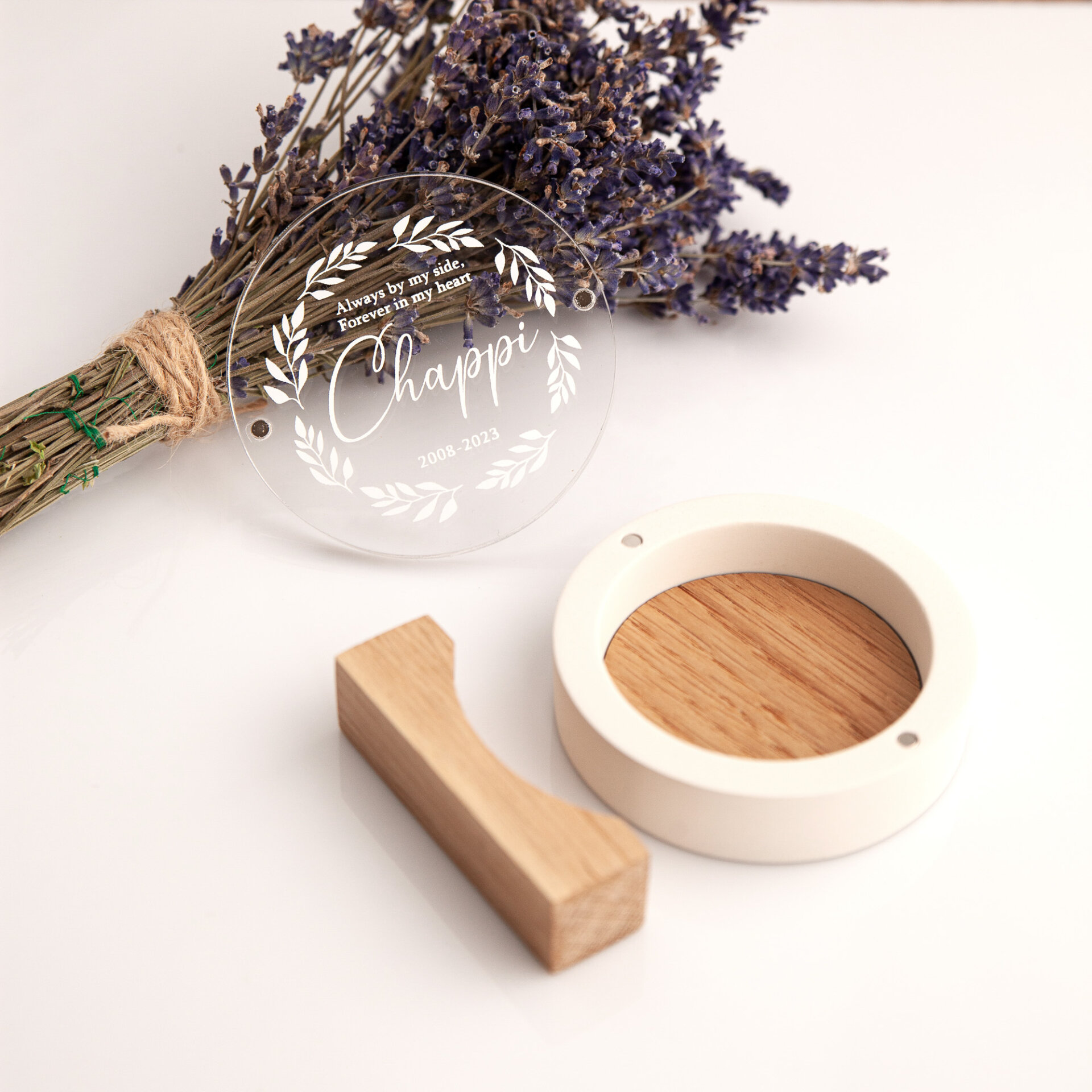 Disassembled white plaster pet keepsake box showing UV printed acrylic lid, empty oak base with magnets, and wooden stand next to dried lavender.