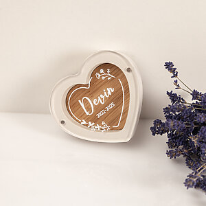 White heart-shaped pet fur keepsake box with Devin name and dates engraved, standing next to lavender.