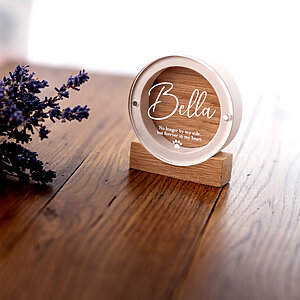 Round white plaster dog fur keepsake gift named Bella displayed on a rustic wooden table with dried lavender.